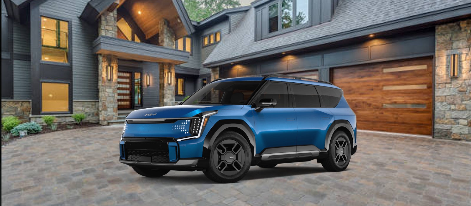 Blue Kia EV9 3-row SUV parked in front of a modern home